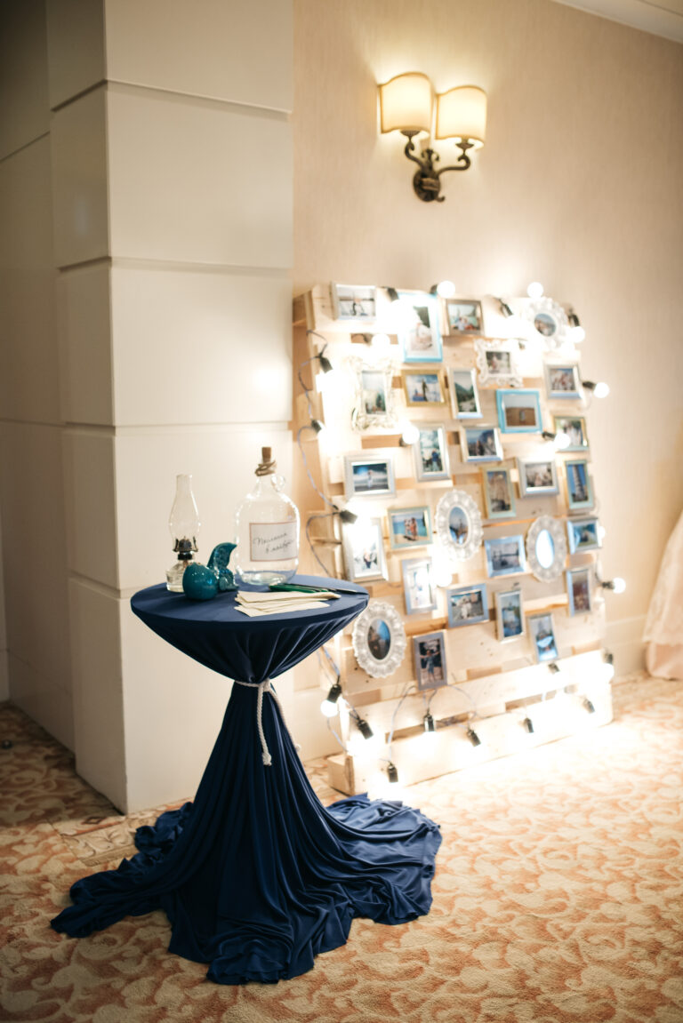 Blue table stands before wall with photos and lights